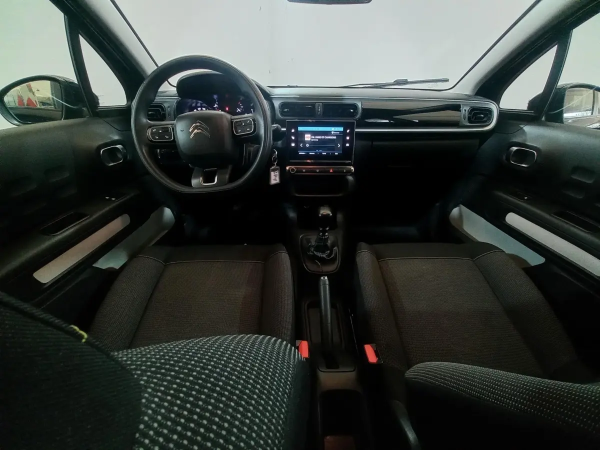 Vue intérieure avant de la Citroën C3 2024 noire, montrant le volant multifonctions et l’écran tactile central.