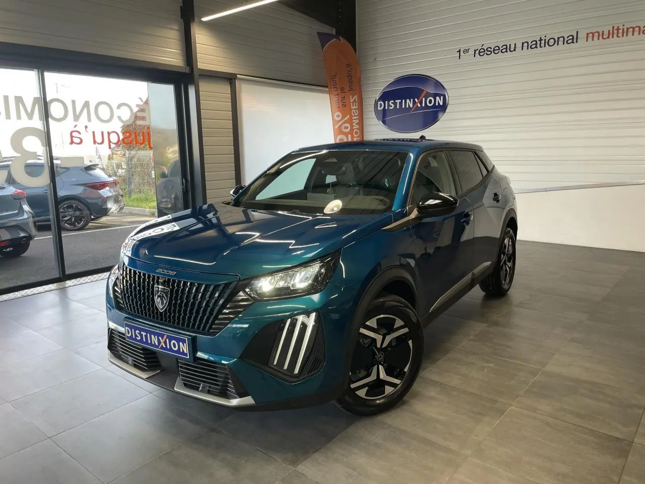 Peugeot 2008 bleu en 3/4 avant droit, avec calandre noire et feux LED distinctifs allumés.