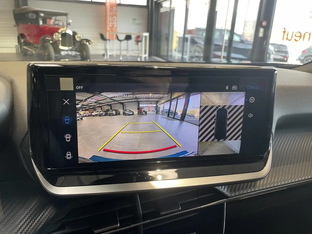 Écran tactile intérieur montrant la caméra de recul et la vue 360° du Peugeot 2008 hybride bleu en stationnement.