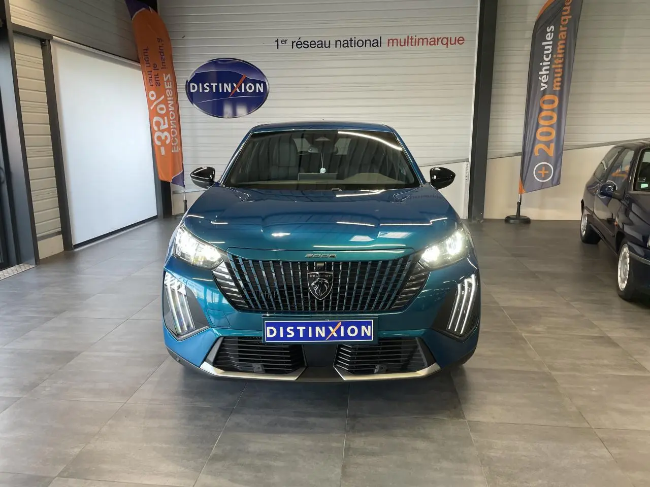 Vue frontale d'un Peugeot 2008 bleu métallisé avec calandre noire et feux LED allumés en showroom.