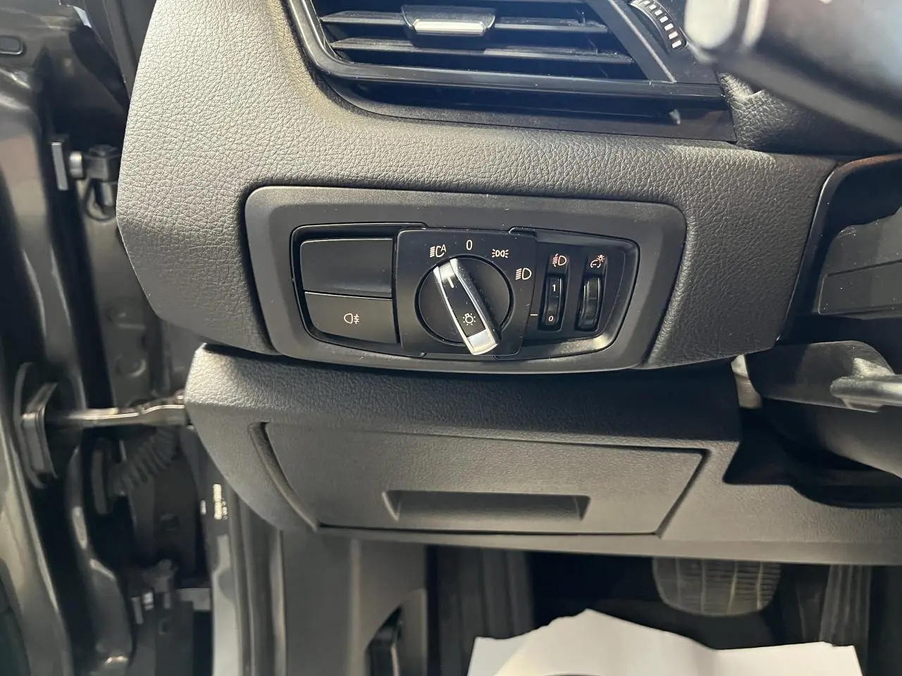 Commande des phares en gros plan sur tableau de bord noir d'une BMW Série 2 225xe Active Tourer gris 2018.