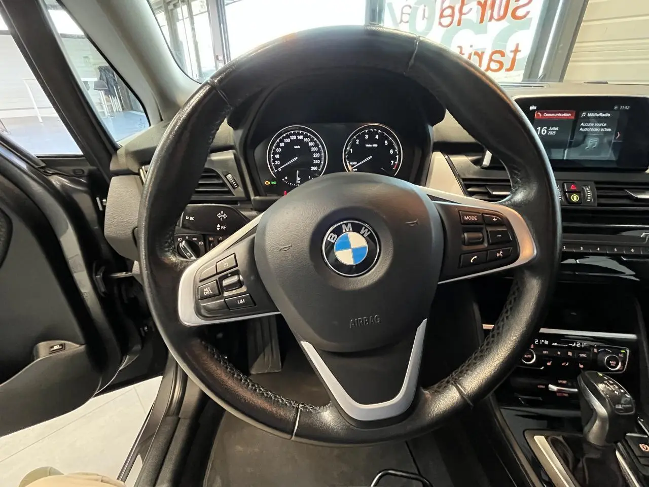 Vue rapprochée du volant noir de la BMW Série 2 225xe Active Tourer 2018 avec tableau de bord et console centrale visibles.