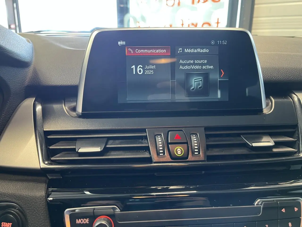 Vue rapprochée de l'écran multimédia et des commandes centrales du tableau de bord d'une BMW Série 2 gris 225xe Active Tourer 2018.