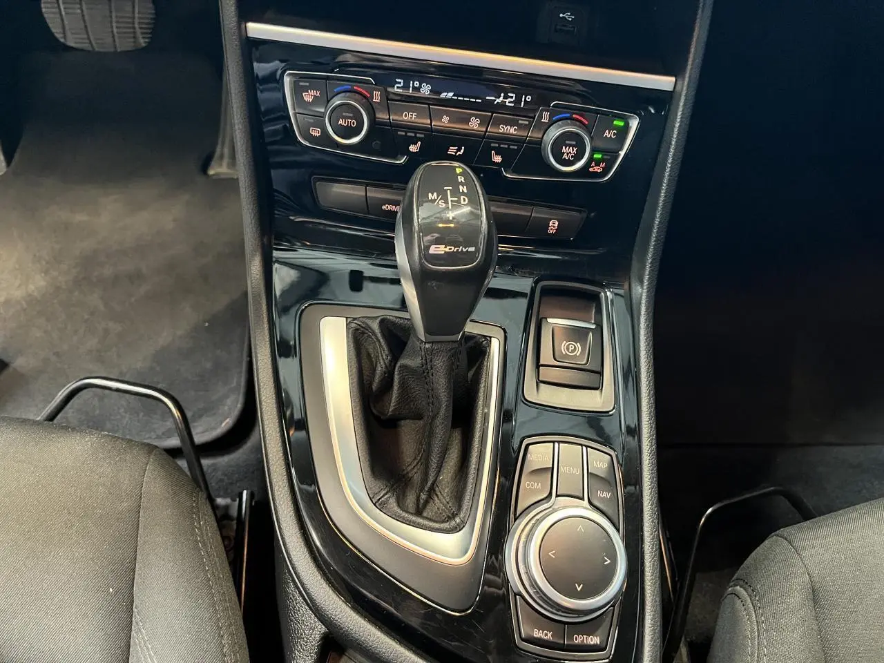 Gros plan sur la console centrale d'une BMW Série 2 225xe gris, avec levier de vitesse automatique eDrive et commandes multimédia.