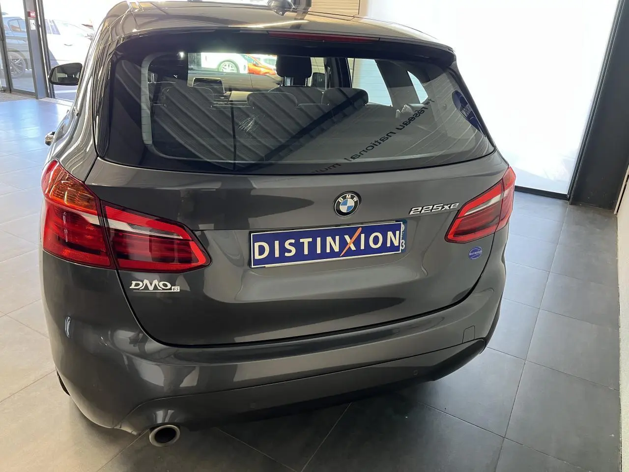 Vue arrière d'une BMW Série 2 225xe Active Tourer grise, avec feux rouges et logo distinctif sur hayon.