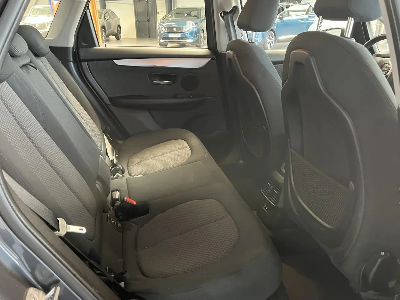 Vue intérieure arrière montrant les sièges tissu gris et les rangements au dos des sièges avant d'une BMW Série 2 Active Tourer 2018.