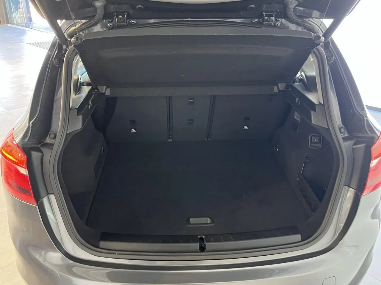 Coffre ouvert vu de l'arrière d'une BMW Série 2 Active Tourer gris 2018 avec intérieur spacieux et banquette rabattable.