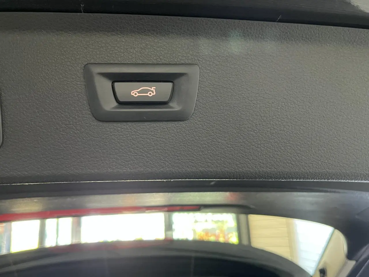 Bouton d'ouverture électrique du coffre sur le hayon intérieur d'une BMW Série 2 Active Tourer gris.