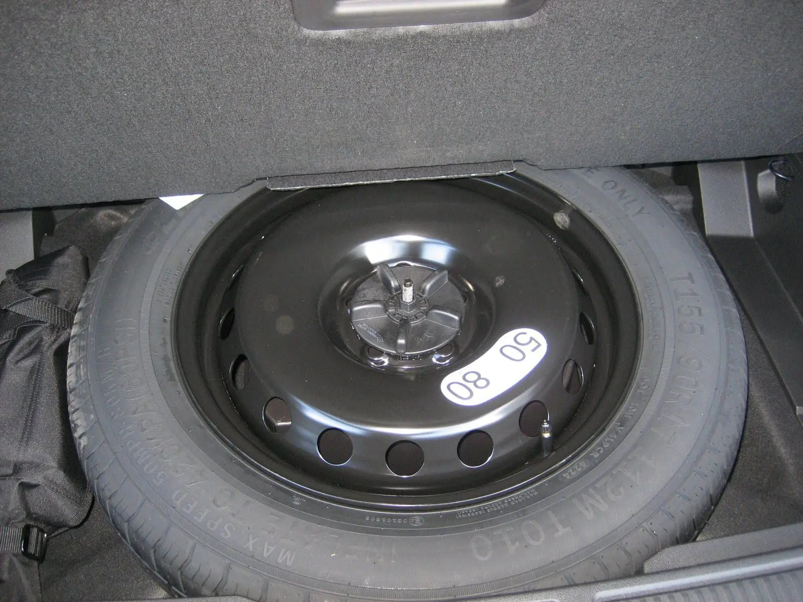 Gros plan sur la roue de secours noire dans le coffre du Renault Austral gris schiste 2025 hybride.
