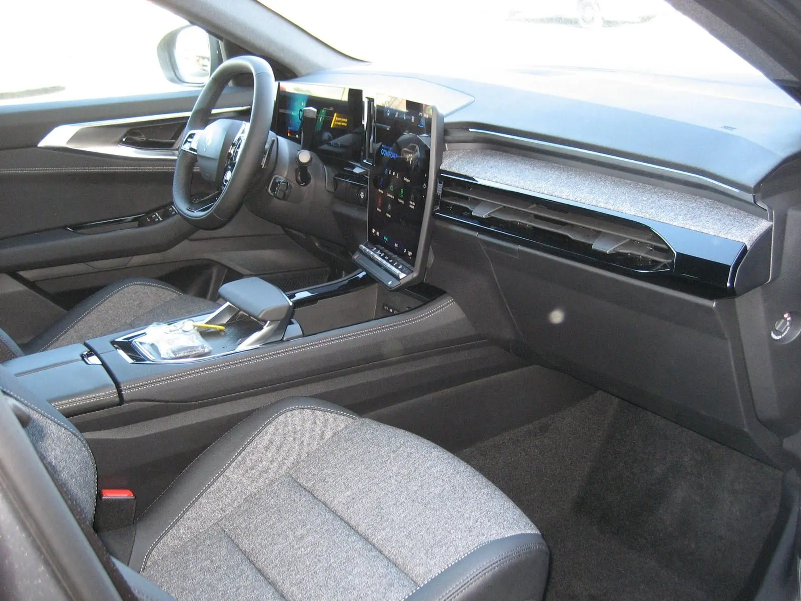 Intérieur du Renault Austral PH.2 vu côté passager, avec sièges gris et tableau de bord moderne à écran tactile vertical.