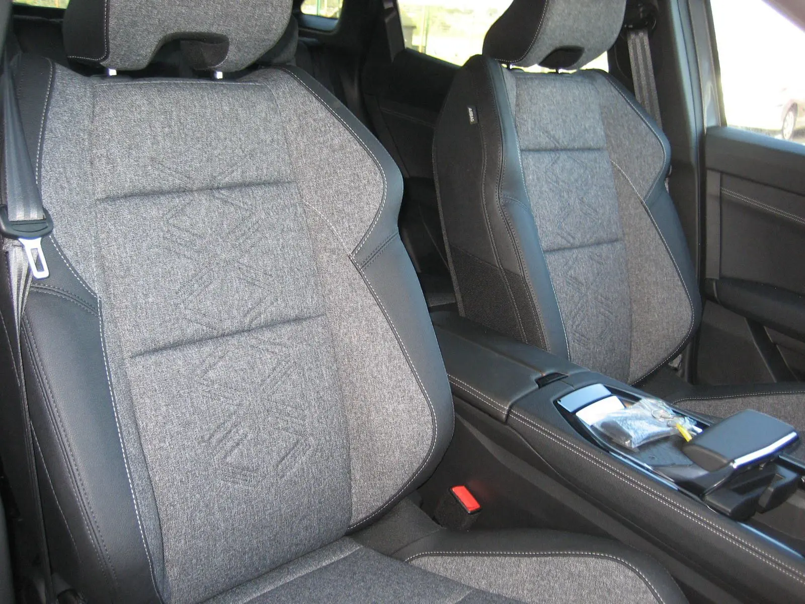 Gros plan sur les sièges avant gris et noirs en tissu et cuir du Renault Austral PH.2 TECHNO E-TECH 2025, vue côté droit.