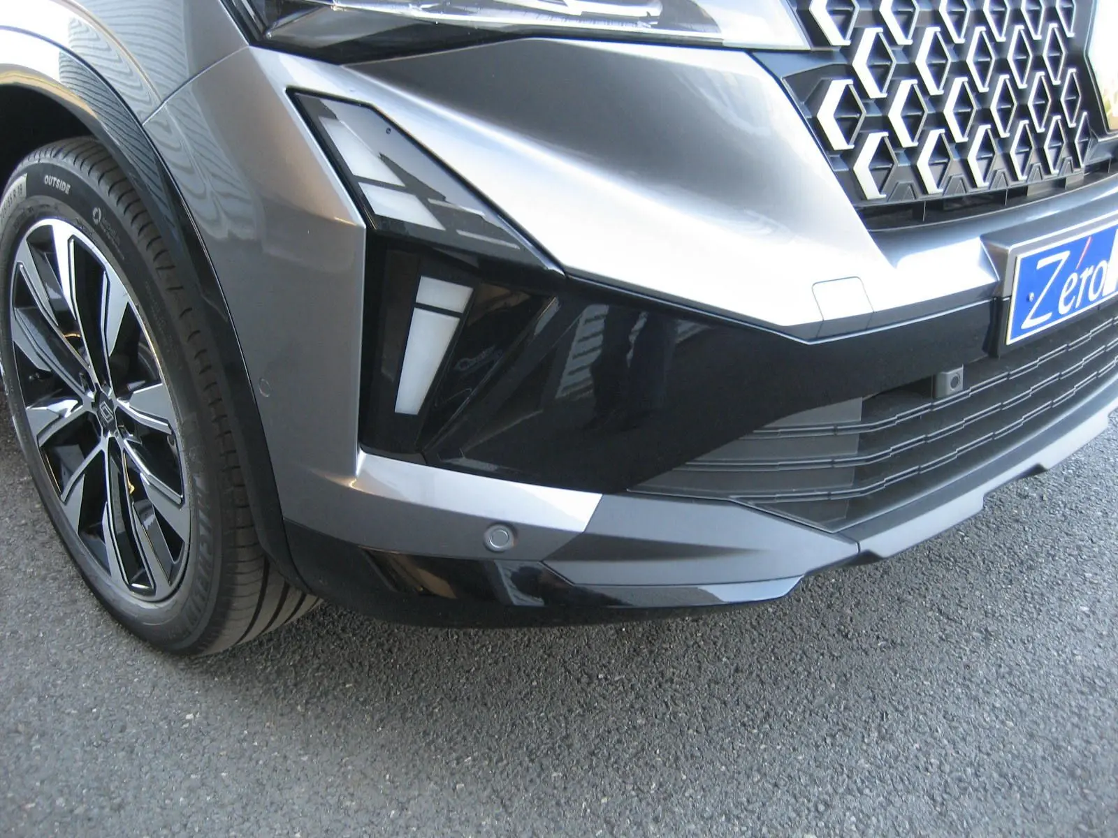 Gros plan sur l'avant droit gris schiste du Renault Austral PH.2 avec calandre hexagonale et jante noire brillante.