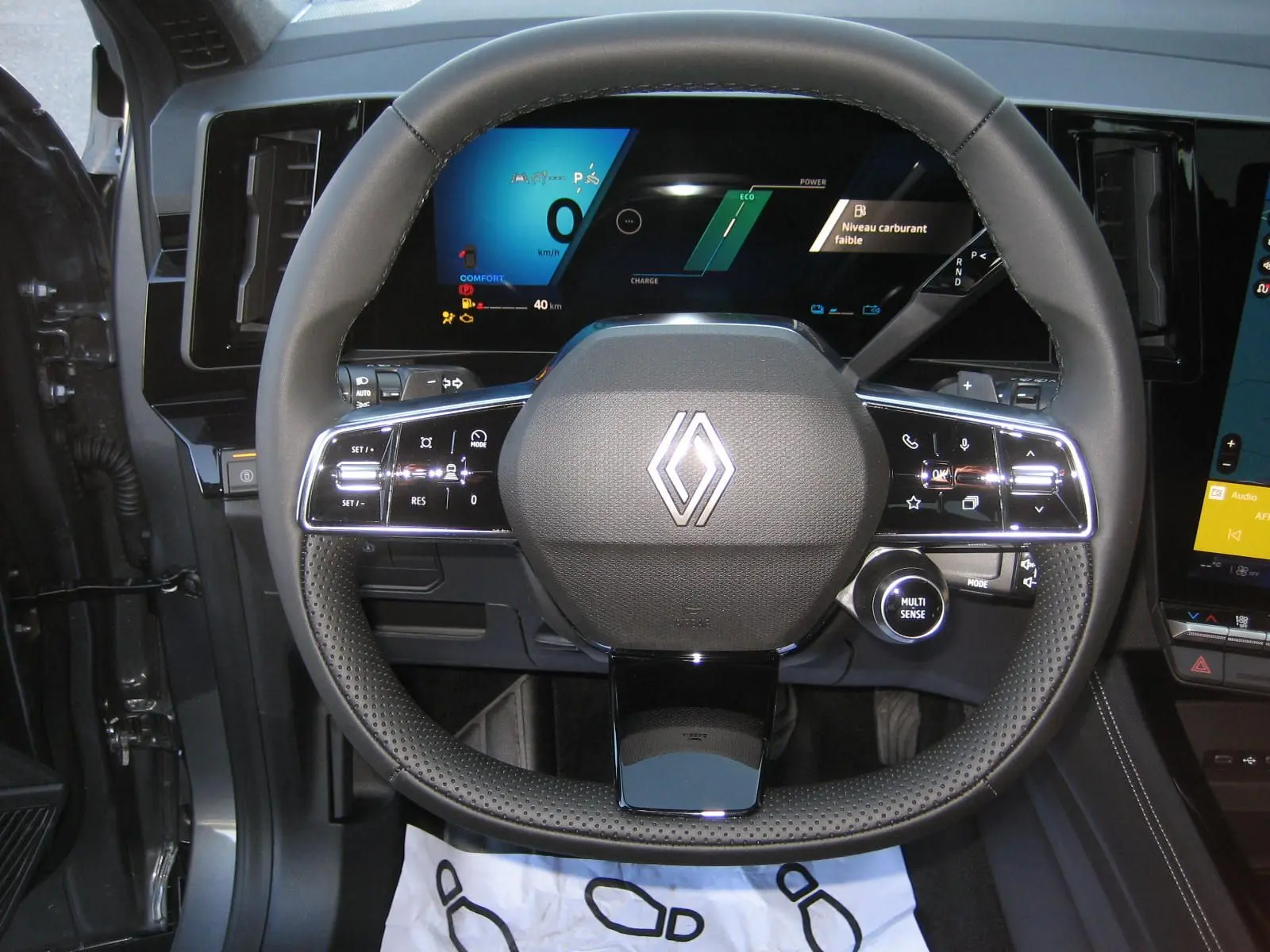 Vue rapprochée du volant cuir noir du Renault Austral PH.2 avec tableau de bord numérique allumé en arrière-plan.