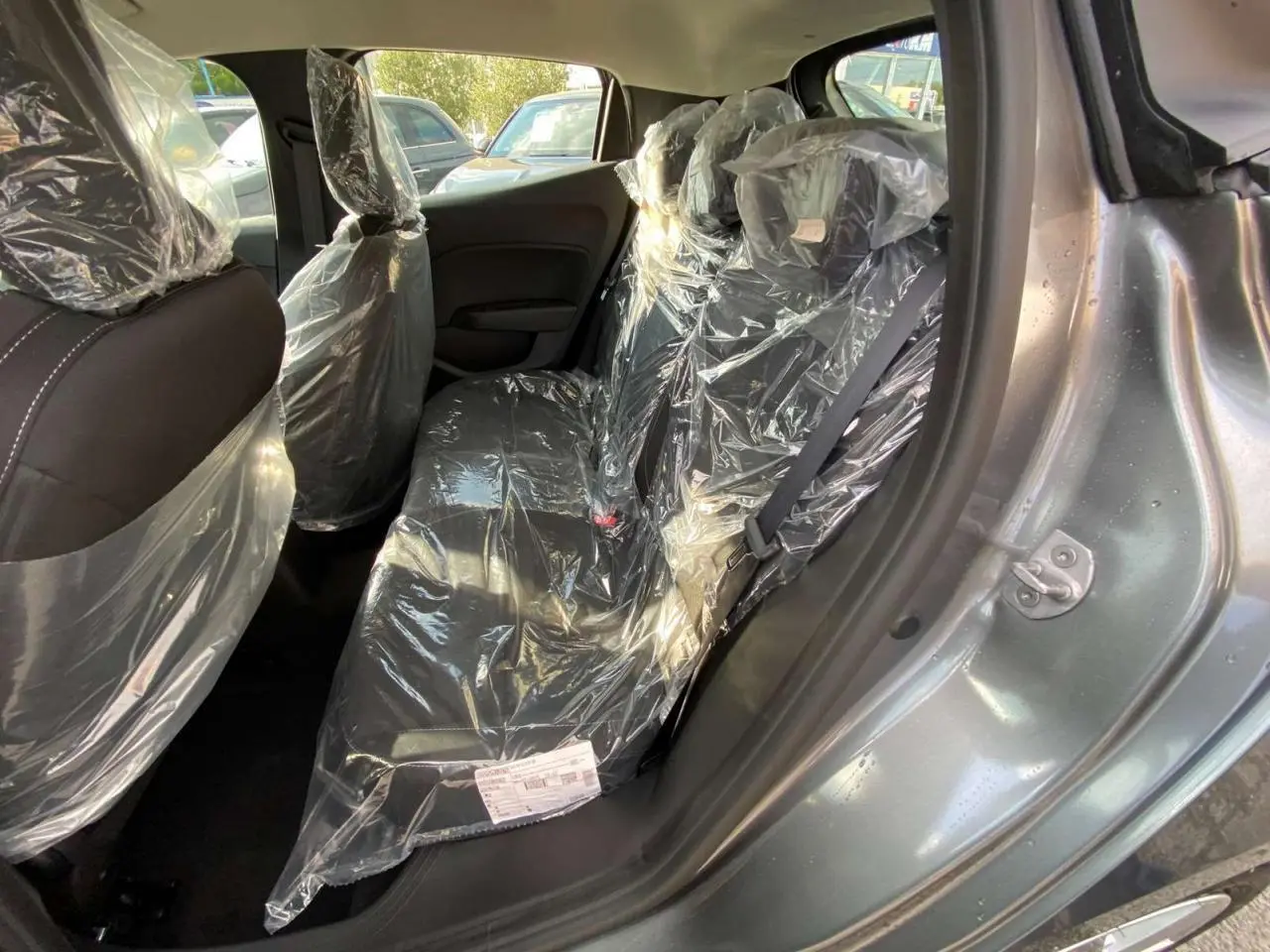 Vue intérieure côté droit de la banquette arrière d'une Renault Clio 2025 gris schiste avec sièges protégés par film plastique.