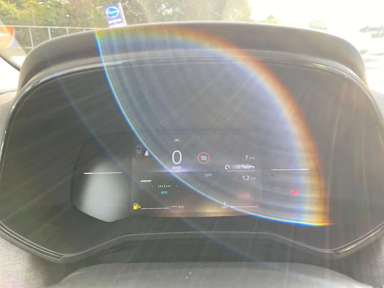 Compteur numérique couleur 7 pouces de Renault Clio 2025, affichant vitesse et alertes, avec reflet lumineux circulaire.