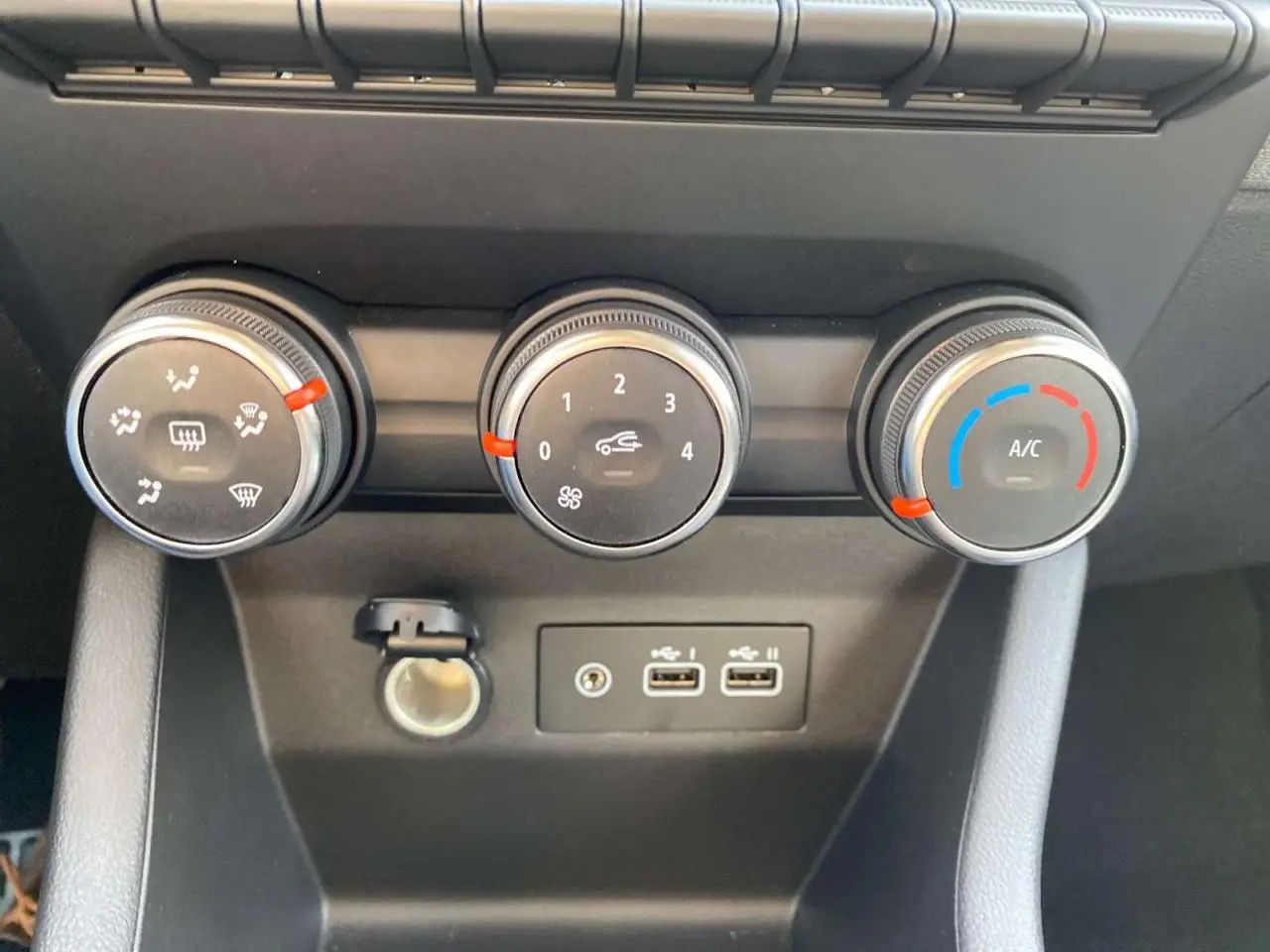 Gros plan sur les commandes de climatisation manuelle et les ports USB de la Renault Clio 1.5 Blue dCi noire.