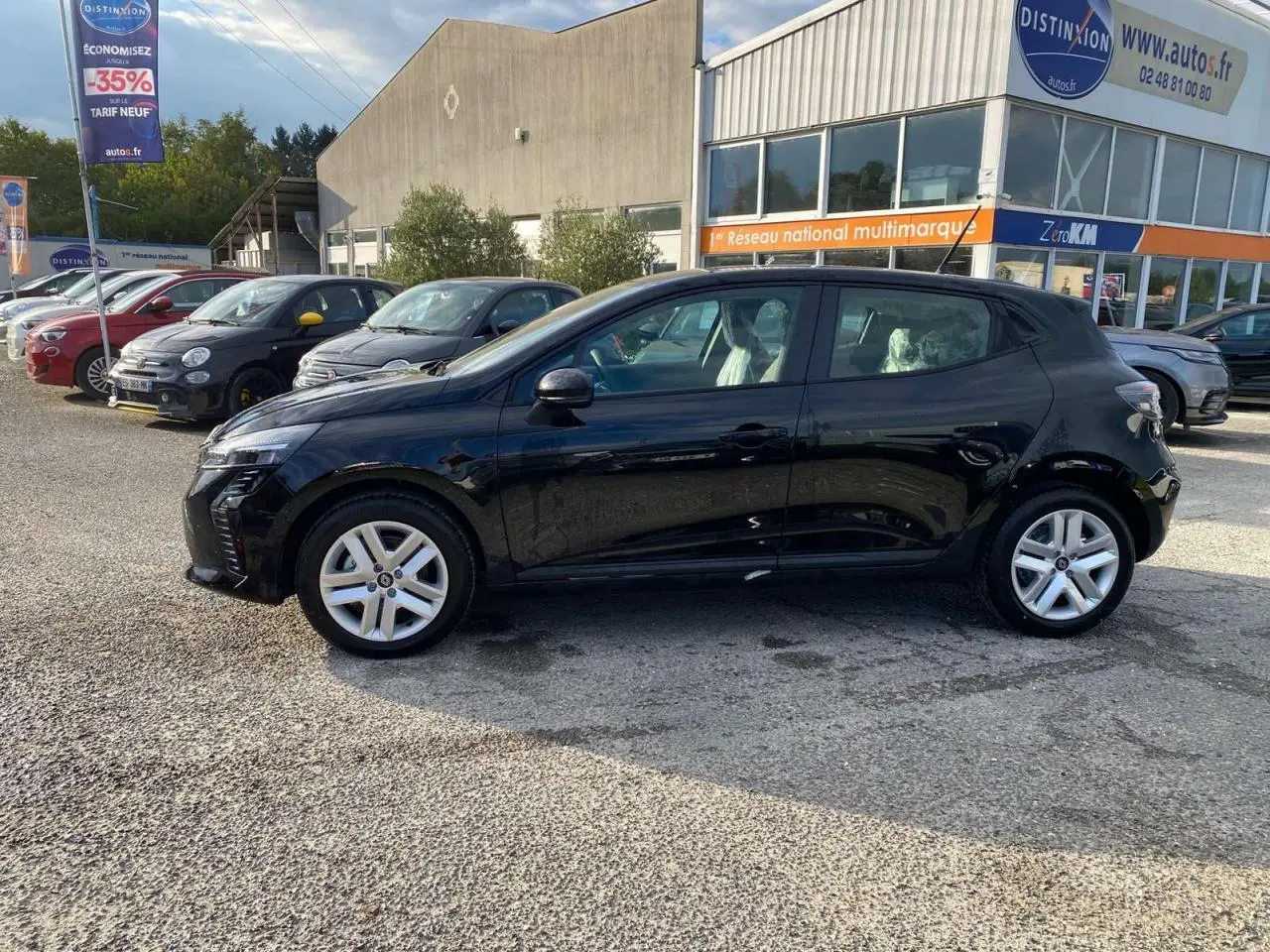 Renault Clio 1.5 Blue dCi 2025 noir étoilé vue de profil côté gauche sur parking devant concession multimarques.