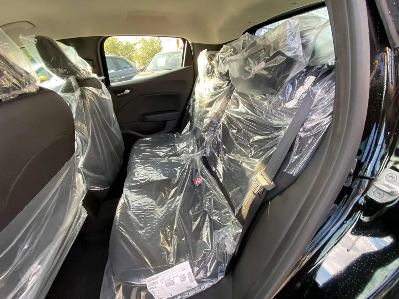 Vue intérieure côté droit de la banquette arrière noire protégée par des housses plastiques dans une Renault Clio 2025 Noir Étoile.