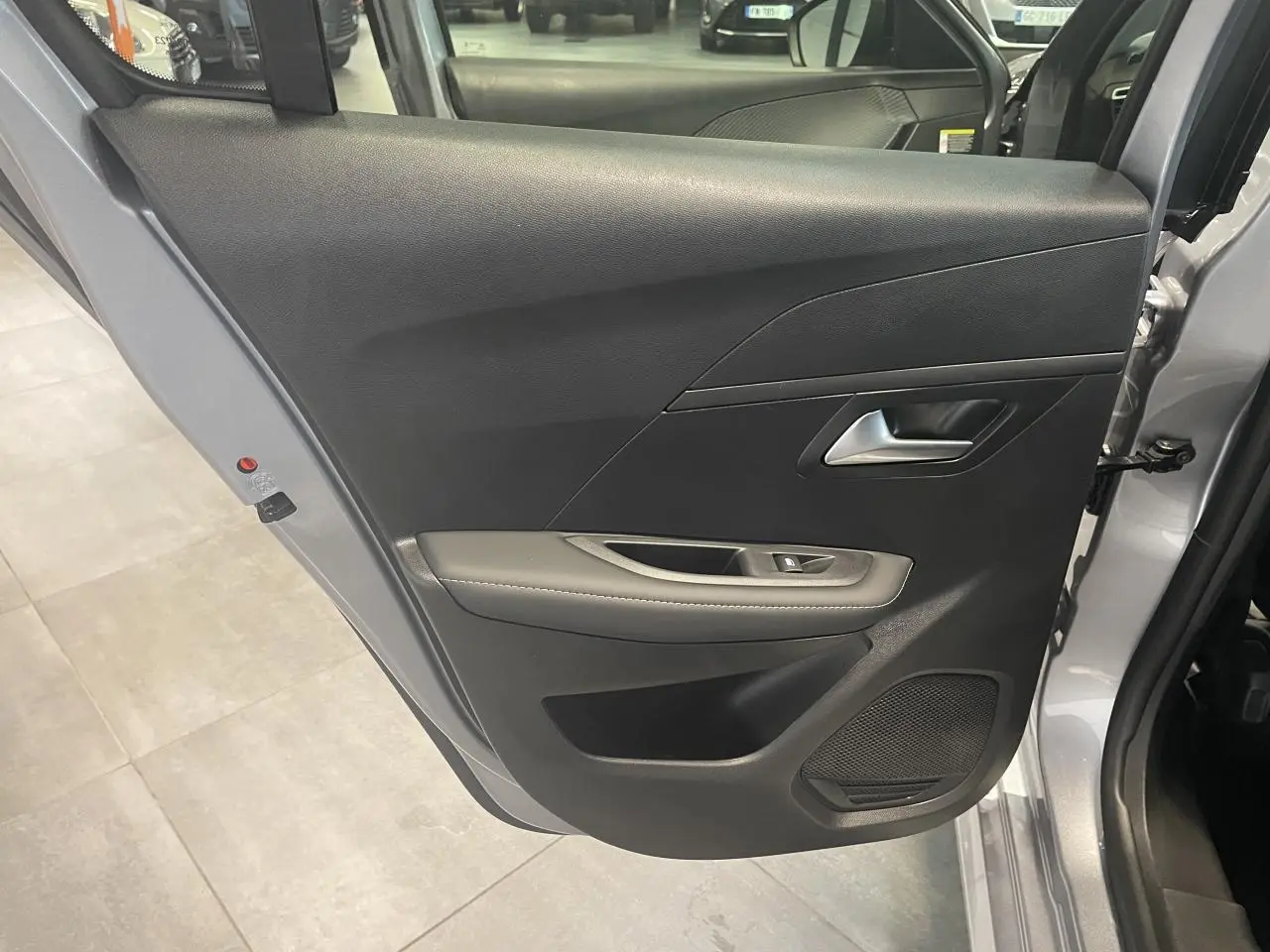 Vue rapprochée de la porte arrière droite gris Artense de la Peugeot 208 1.2i Hybrid Allure avec habillage noir et accoudoir gris.