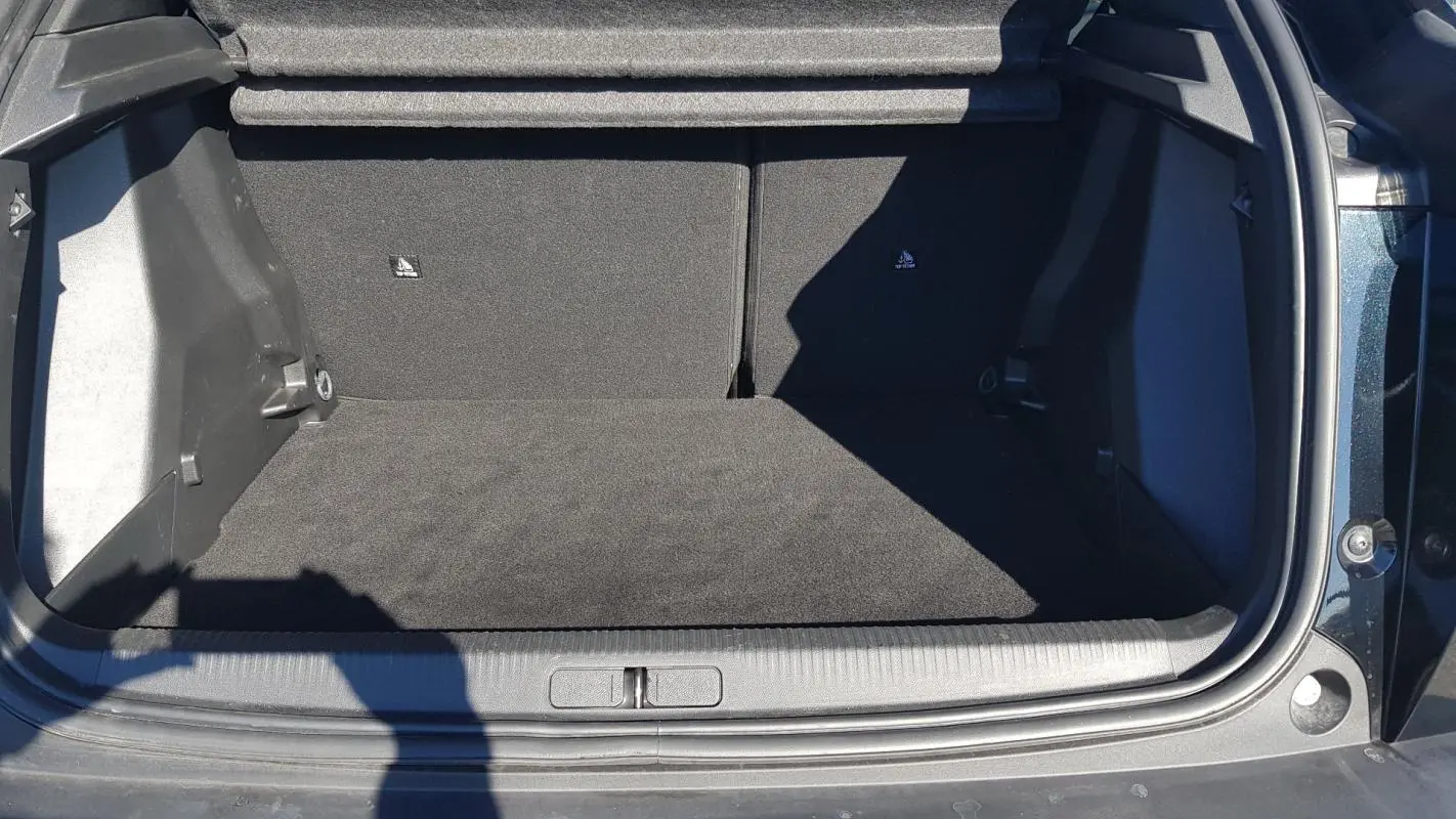 Coffre ouvert d’un Peugeot 2008 Hybrid 145 noir, vue de l’arrière montrant l’espace de chargement vide.