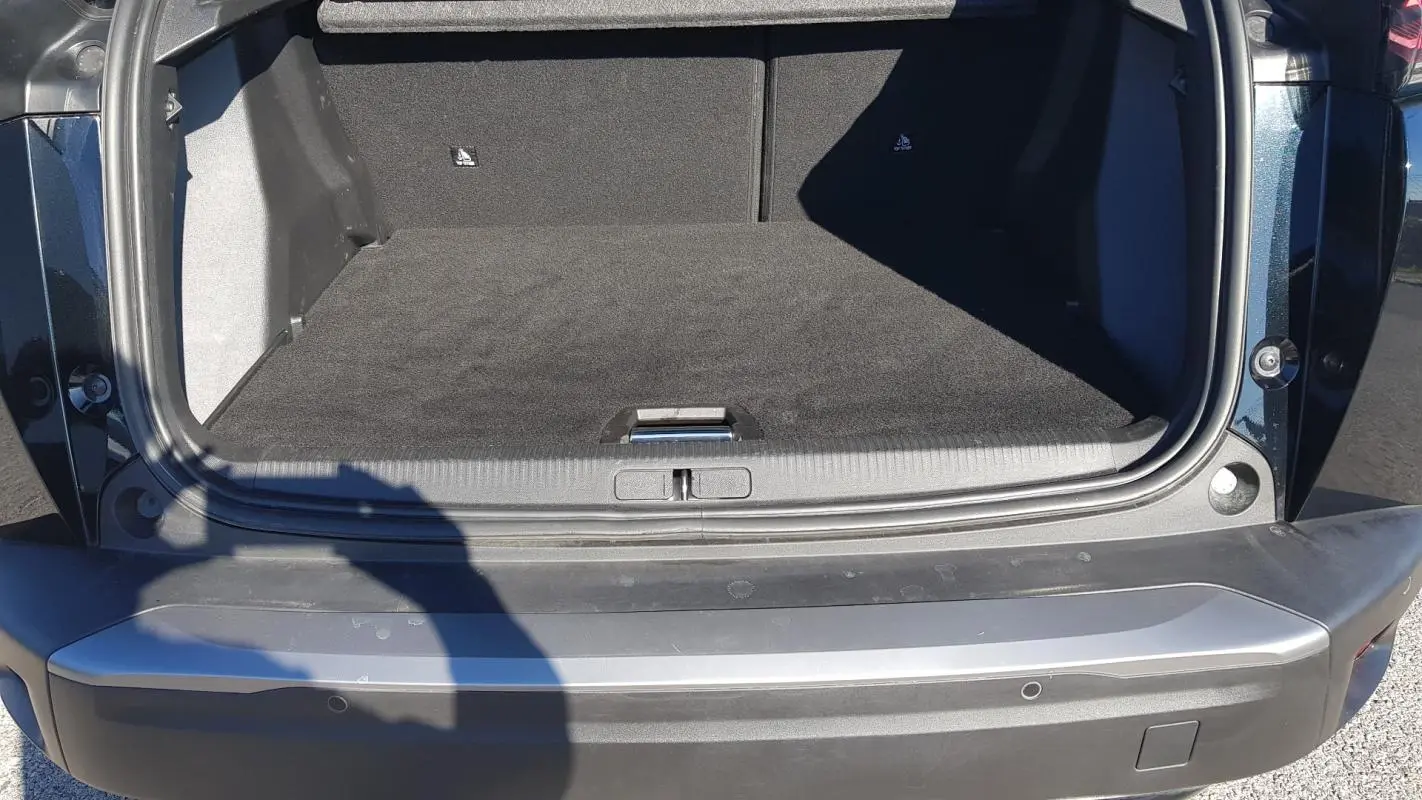 Coffre ouvert vu de l'arrière d'un Peugeot 2008 Hybrid 145 noir, montrant l'espace de chargement vide.