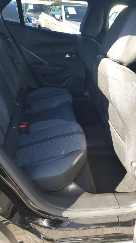 Vue intérieure arrière côté gauche du Peugeot 2008 Hybrid 145 e-DCS6 Allure noir, montrant les sièges arrière et la porte ouverte.