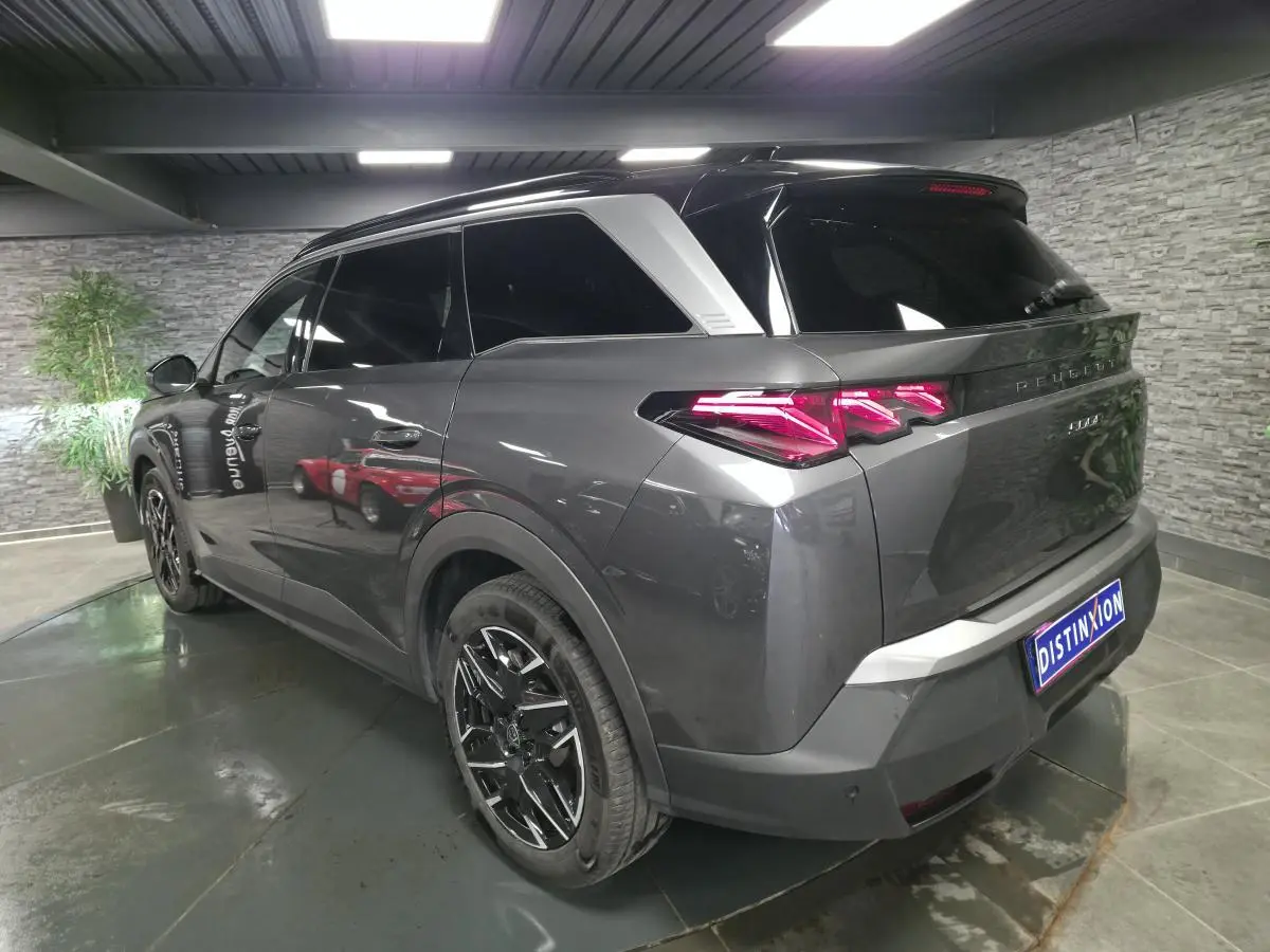 Vue 3/4 arrière droite du Peugeot 5008 gris métallisé avec feux arrière LED en forme de griffes et jantes alliage noires.