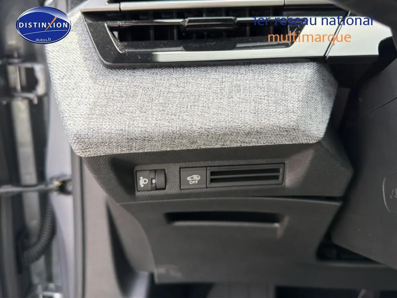Détail des commandes sous la planche de bord côté gauche avec tissu gris et plastique noir du Peugeot 5008 Hybrid 145.