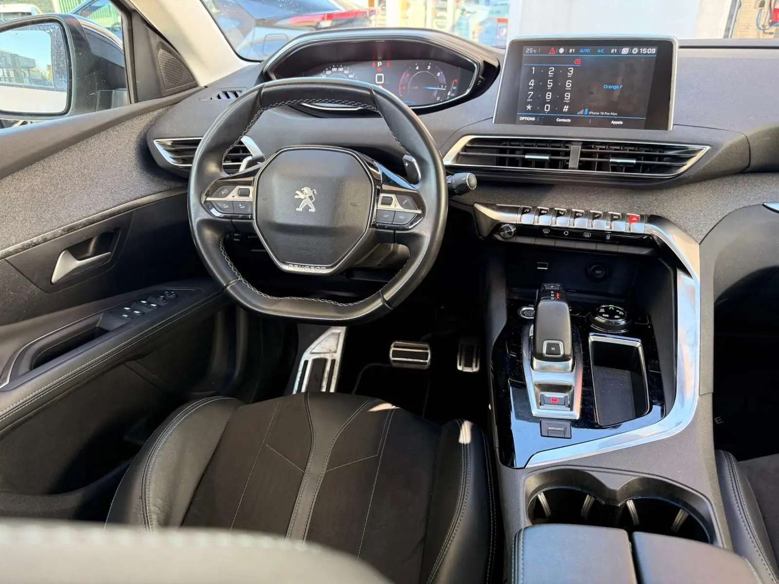 Vue frontale d'un Peugeot 3008 blanc nacré avec calandre noire et logo lion, sur parking extérieur ensoleillé.