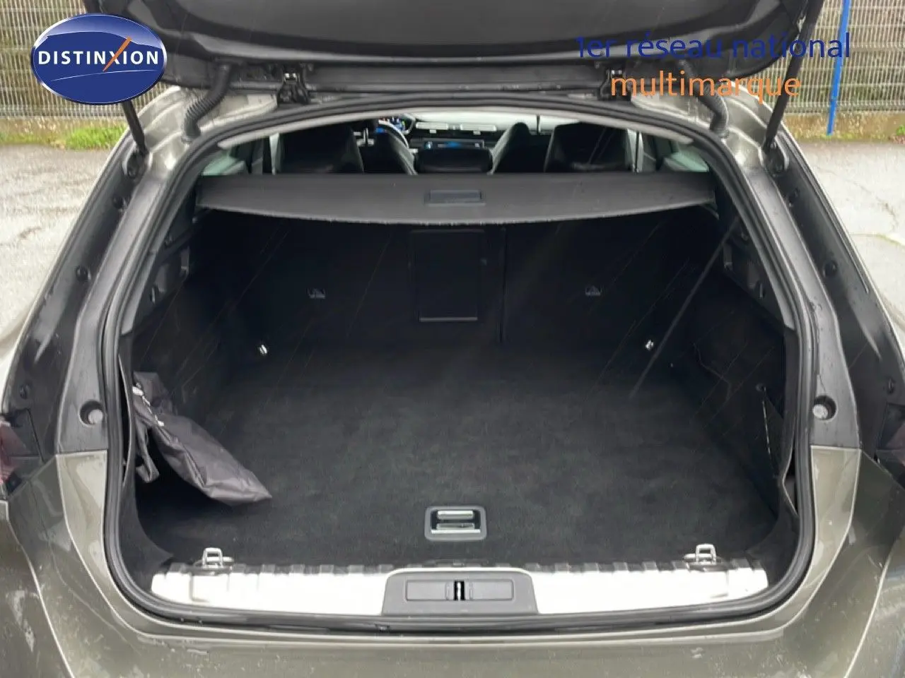 Coffre ouvert vu de l'arrière d'une Peugeot 508 SW gris Amazonite métal, montrant un espace de chargement spacieux et propre.