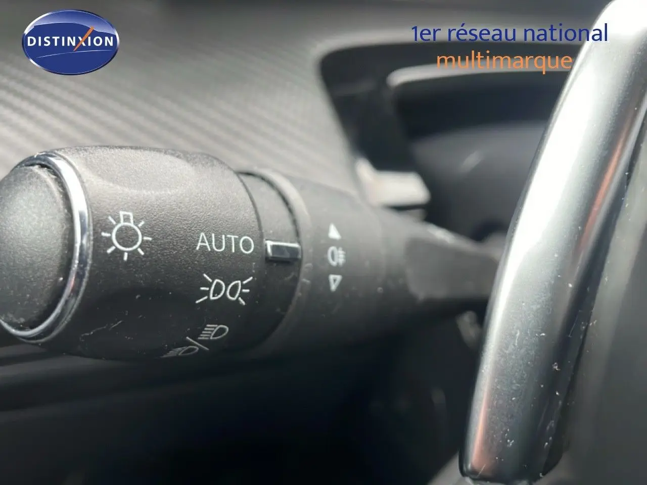 Gros plan sur la commande des phares automatiques à gauche du volant dans l’habitacle d’une Peugeot 508 SW gris Amazonite.