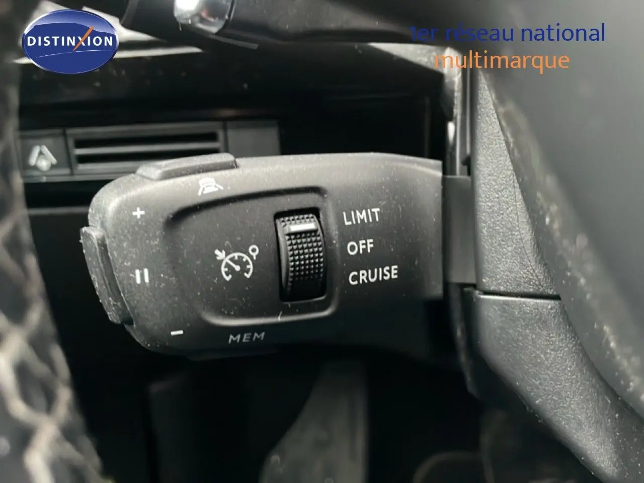 Gros plan sur la commande de régulateur de vitesse à gauche du volant d’un Peugeot 508 SW gris Amazonite 2020.