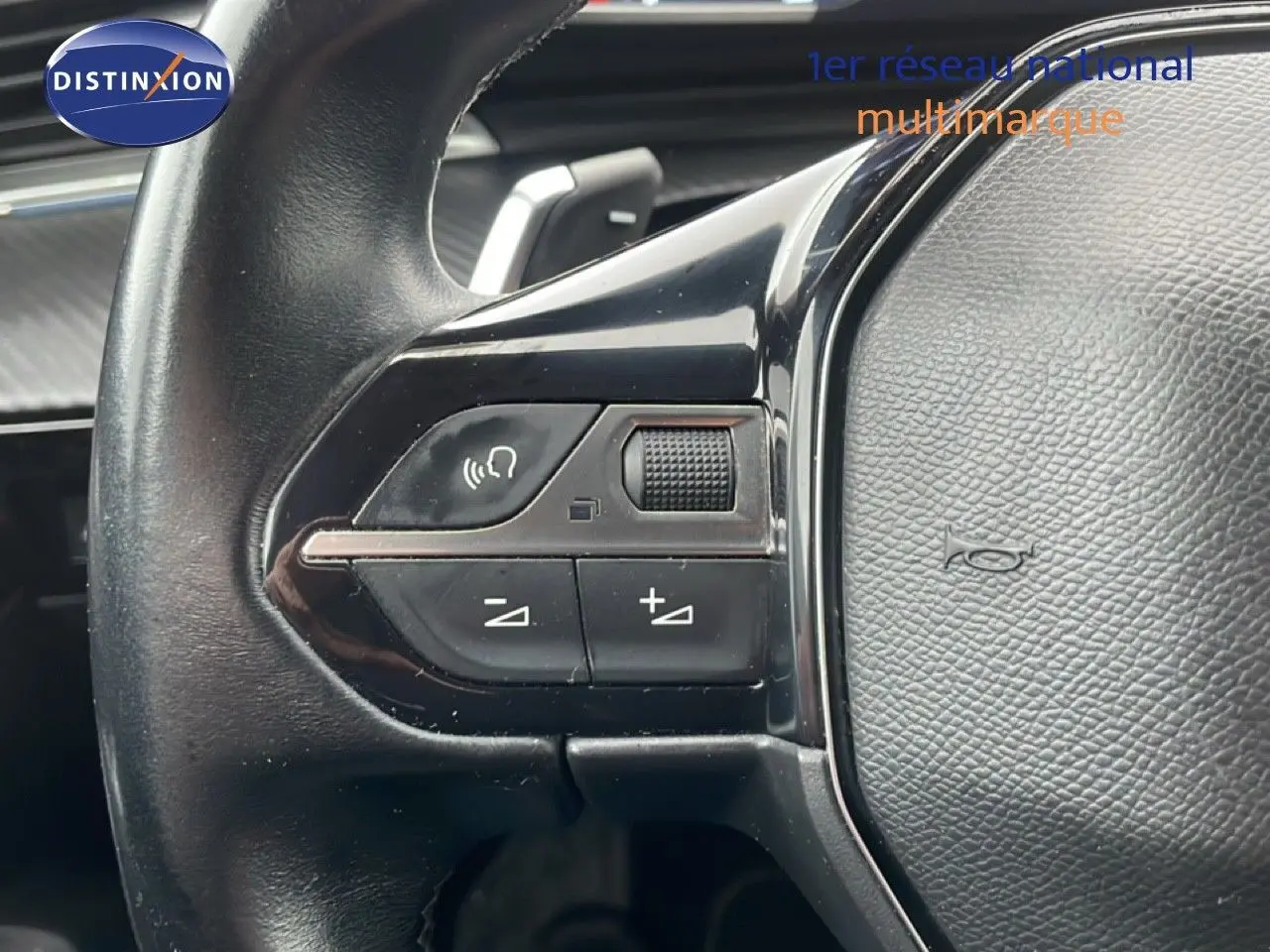 Gros plan sur les commandes au volant du Peugeot 508 SW gris Amazonite, montrant les boutons de volume et de commande vocale.