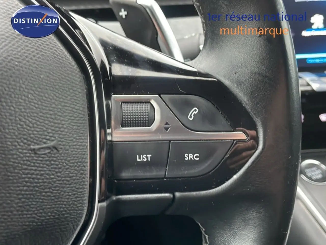 Gros plan sur les commandes gauche du volant en cuir noir de la Peugeot 508 SW 2020, avec boutons de téléphone et liste.