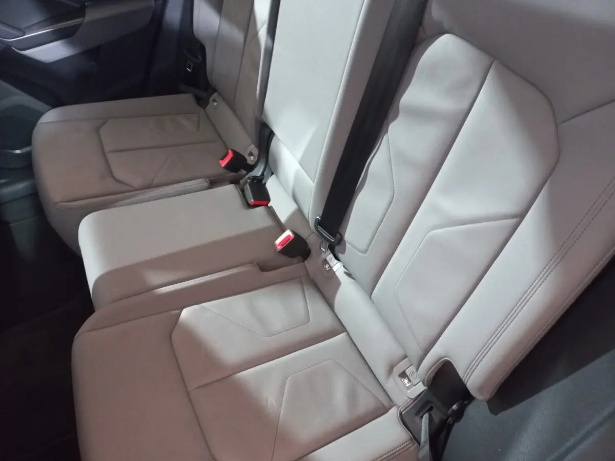 Vue rapprochée de la banquette arrière grise de l'Audi Q3 45 TFSI E 245 S tronic S line avec ceintures et boucles rouges.