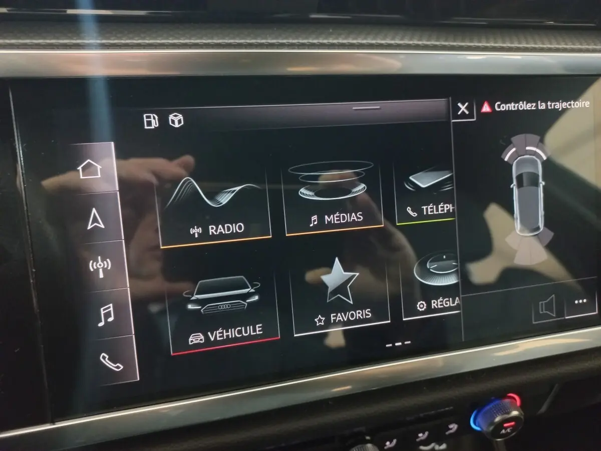 Écran tactile central de l’Audi Q3 blanc 45 TFSI E 2021 montrant les options radio, médias et aide au stationnement.