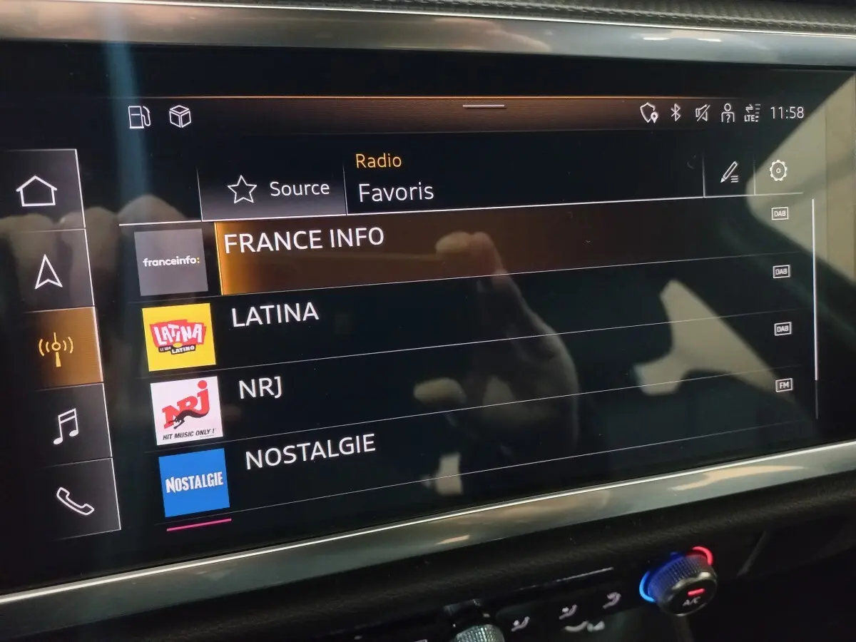 Écran tactile multimédia de l'Audi Q3 blanc, affichant les stations radio favorites en intérieur.