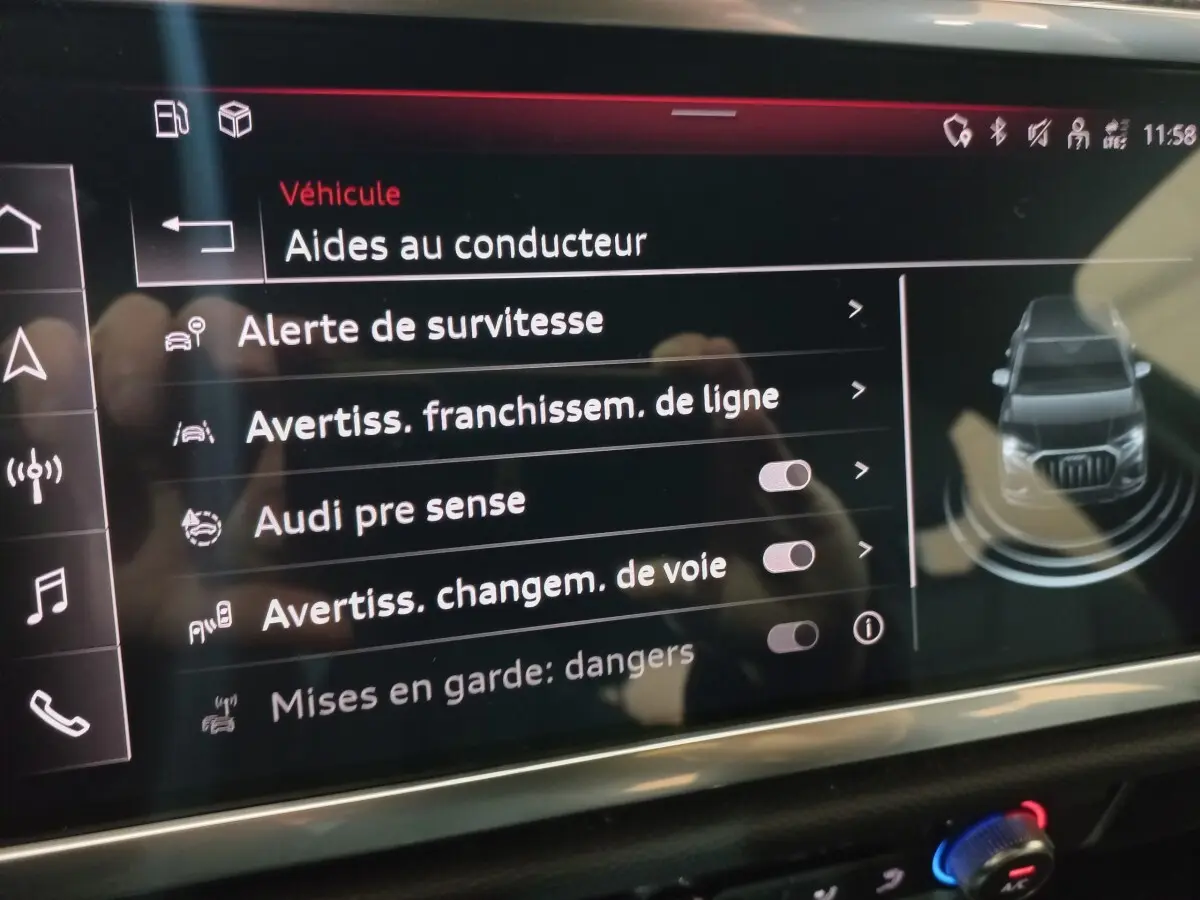 Écran tactile intérieur affichant les aides à la conduite de l’Audi Q3 blanc, vue rapprochée du tableau de bord.