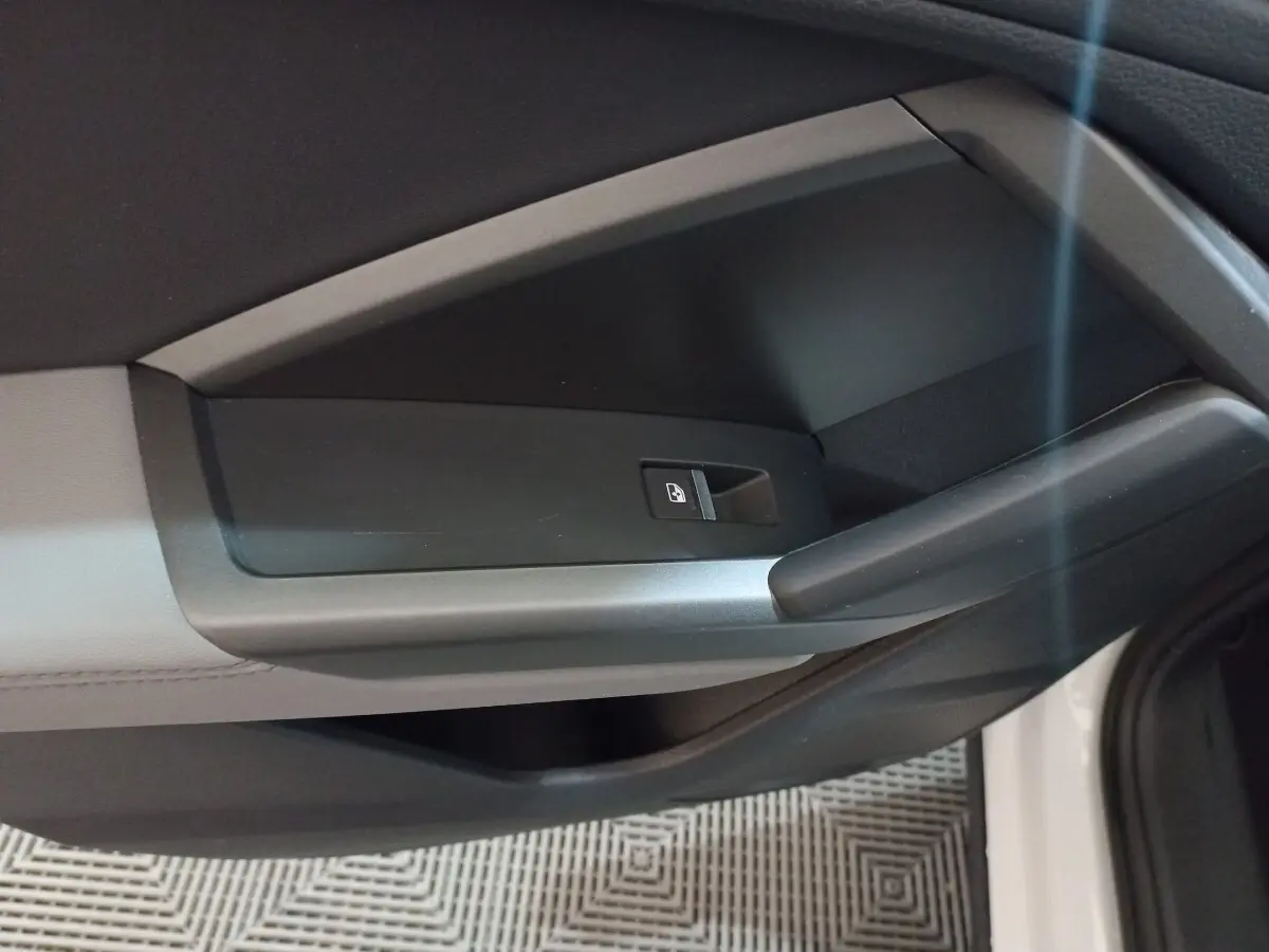 Détail de la poignée intérieure côté droit de la porte d’un Audi Q3 blanc, avec bouton de verrouillage centralisé.