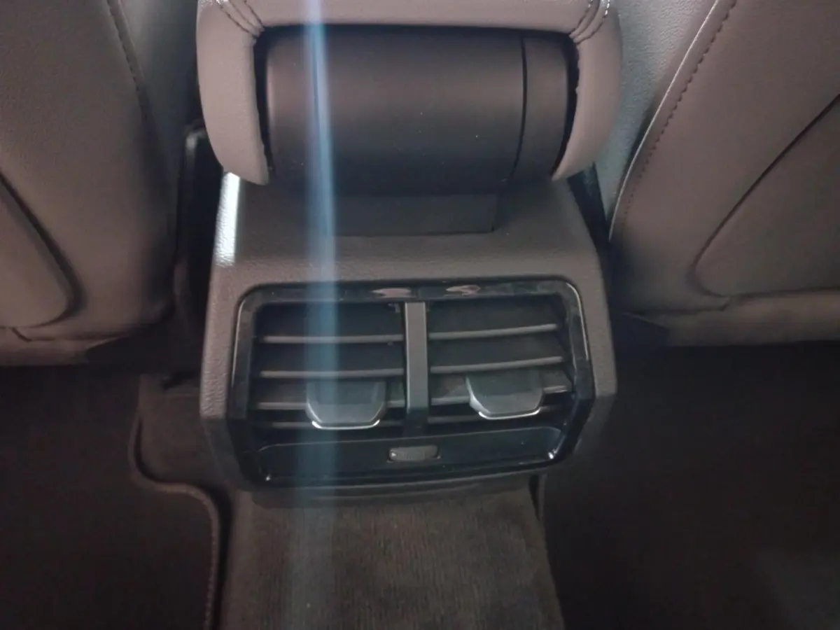 Vue rapprochée des aérateurs arrière noirs entre les sièges avant d’un Audi Q3 blanc hybride rechargeable 2021.