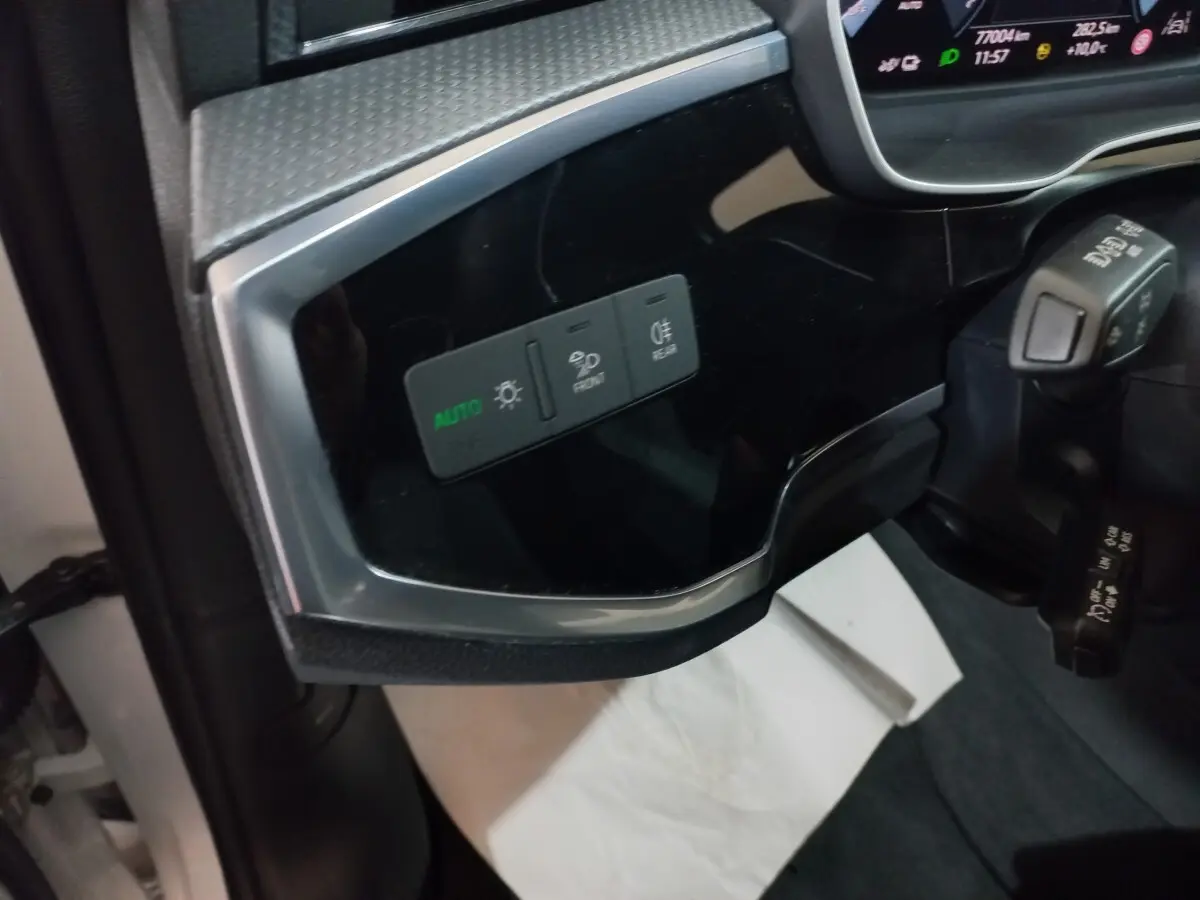 Vue intérieure côté gauche du tableau de bord noir brillant avec commandes d’éclairage de l’Audi Q3 blanc 2021 hybride rechargeable.