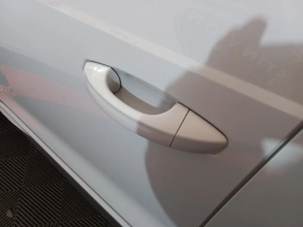 Poignée de porte blanche en gros plan sur le côté gauche d’un Audi Q3 45 TFSI e S line hybride rechargeable.