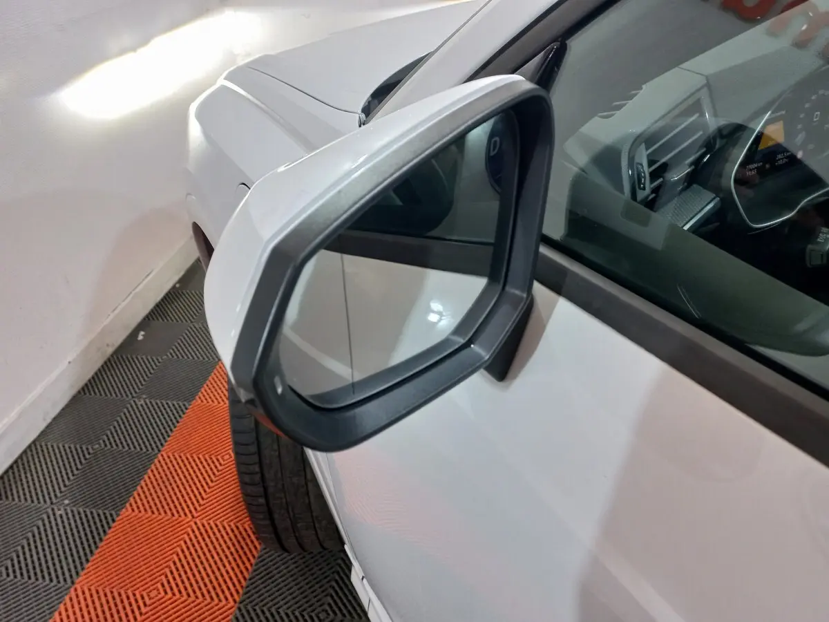 Rétroviseur droit gris sur Audi Q3 blanc hybride rechargeable, vue rapprochée côté avant droit avec intérieur partiellement visible.