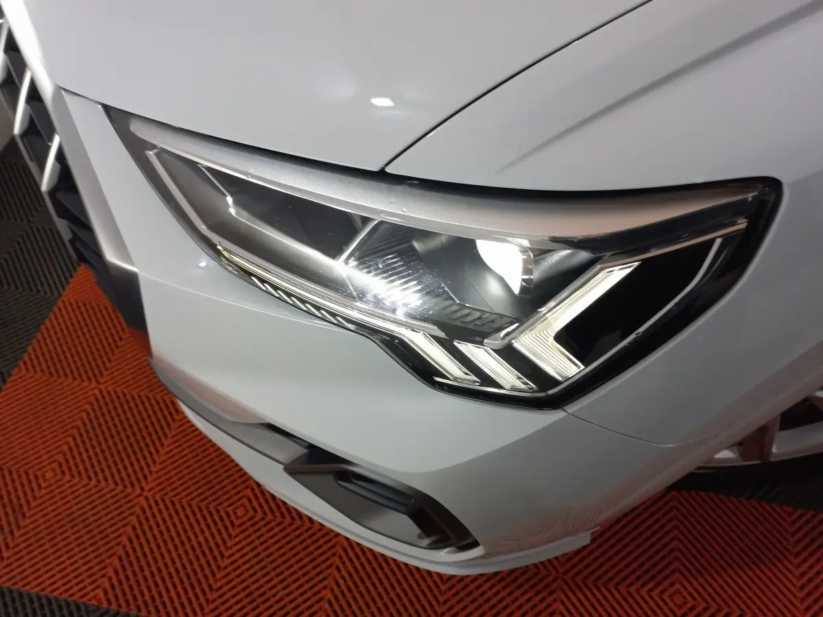 Gros plan sur le phare avant droit blanc d’un Audi Q3 45 TFSI e S line 2021, avec éclairage LED distinctif.