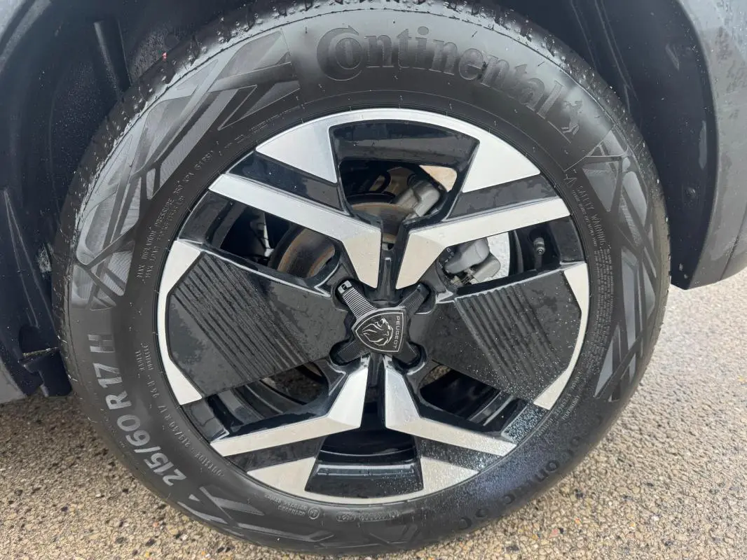 Gros plan sur la jante alliage 17 pouces noire et argentée du Peugeot 2008 Hybrid 145 gris, avec pneu Continental visible.
