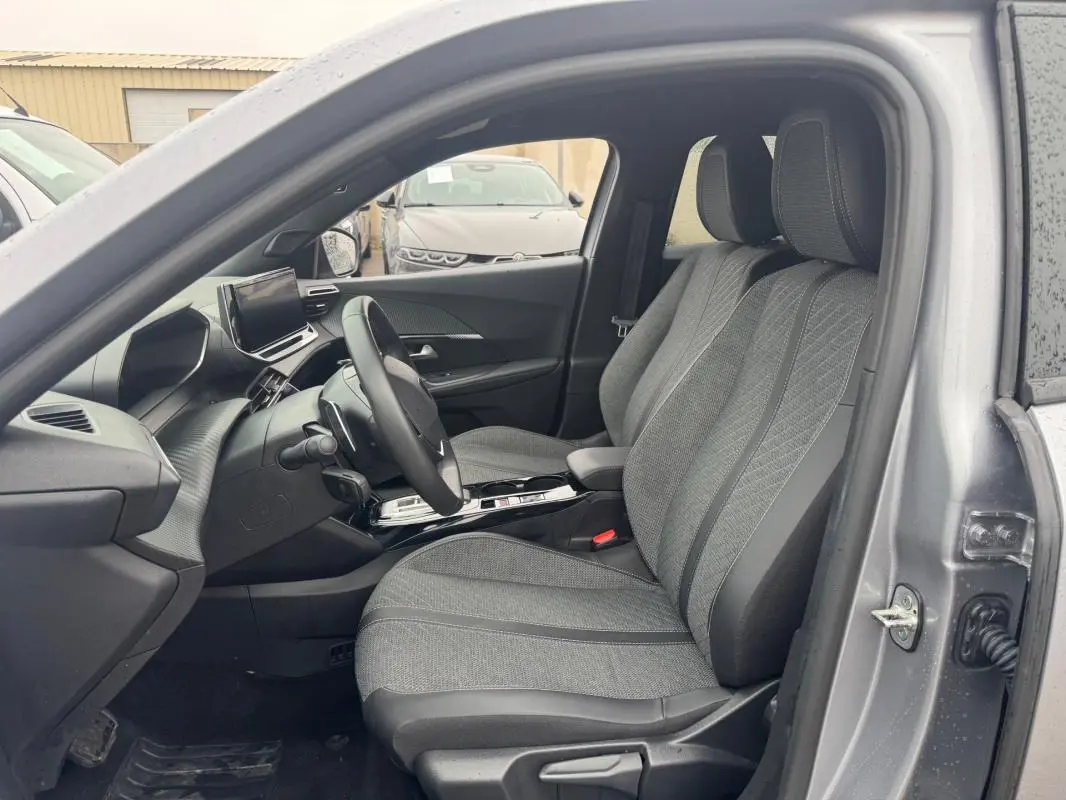 Vue intérieure côté conducteur du Peugeot 2008 gris 2025, montrant les sièges avant et le tableau de bord moderne avec écran tactile.