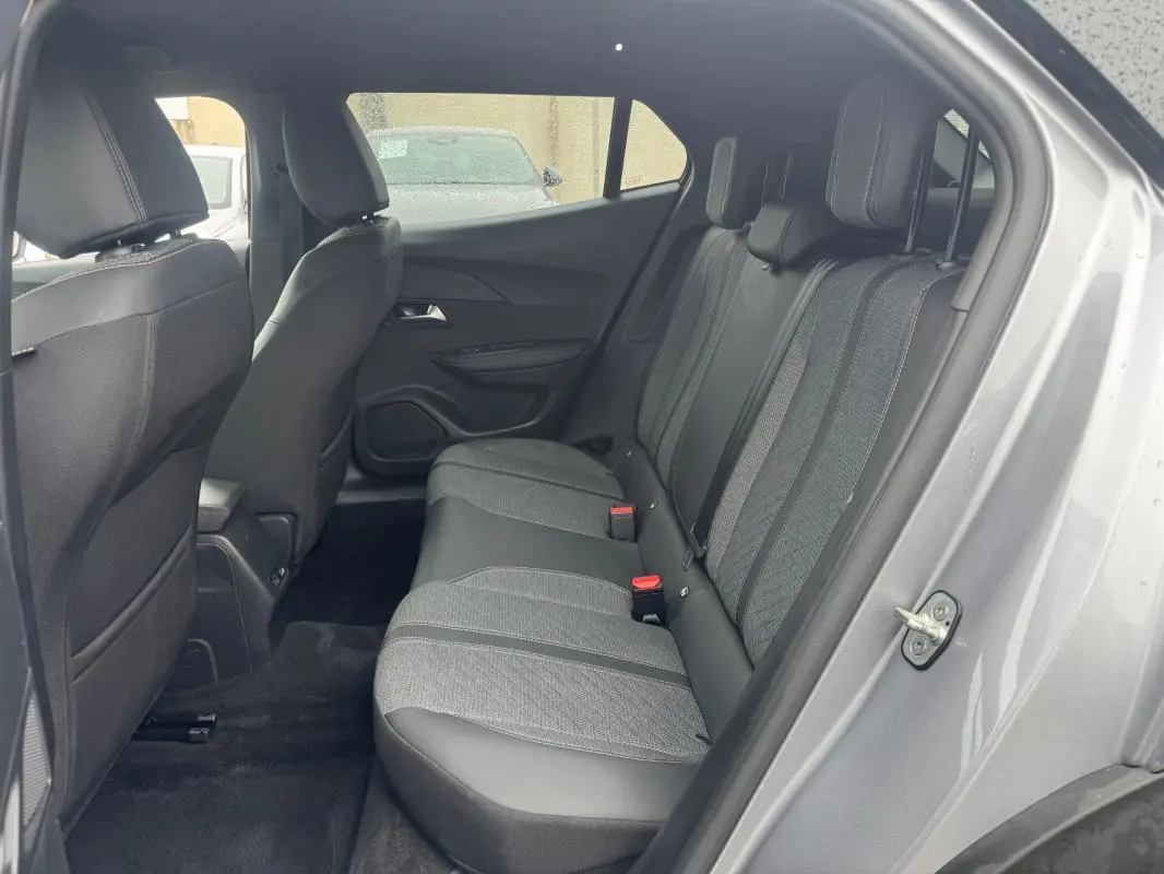 Vue côté droit de l’habitacle arrière du Peugeot 2008 gris 2025, montrant les sièges en tissu et cuir bicolore.