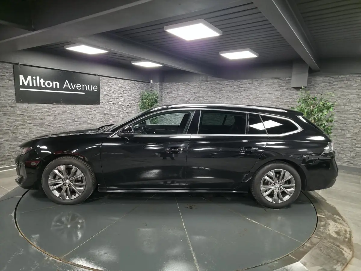 Peugeot 508 SW noire vue de profil côté gauche, avec barres de toit en aluminium et jantes alliage 17 pouces.