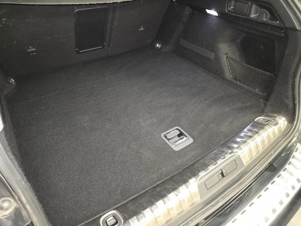 Coffre noir spacieux de Peugeot 508 SW 2019, vue intérieure avec tapis et filet de rangement latéral.