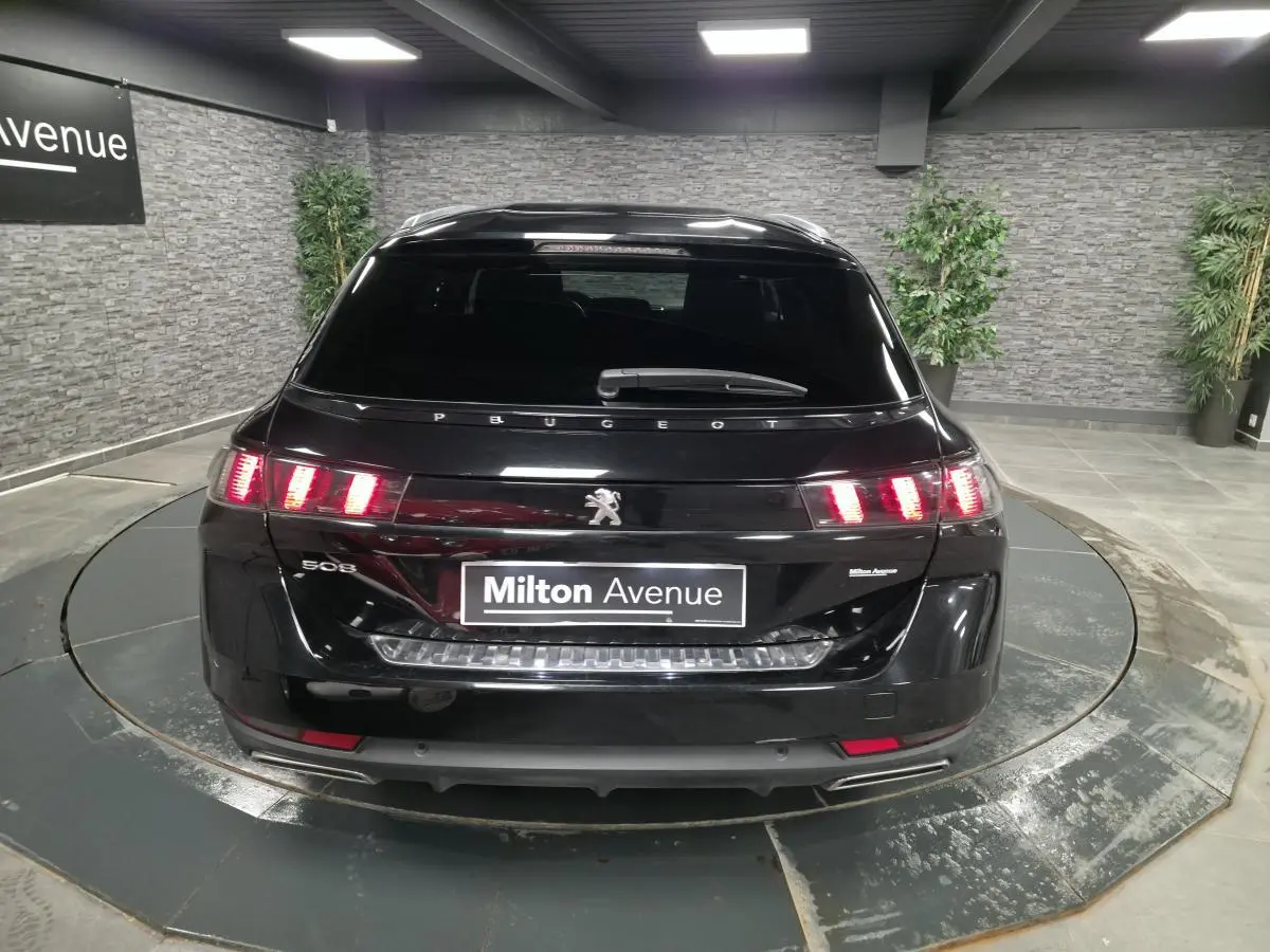 Vue arrière d'une Peugeot 508 SW noire avec feux arrière LED et double sortie d'échappement chromée.
